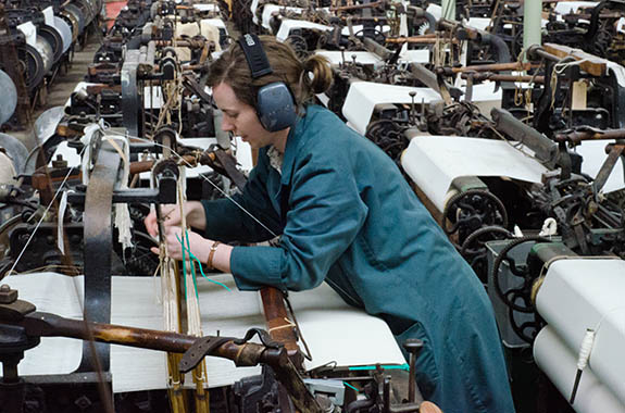 ENG: The Northwest Region, Lancashire, The Pennines, Burnley Borough, Briercliffe, Queen Street Mill, A docent runs a belt-powered loom on a fully functioning factory floor of this steam-powered Victorian textile plant [Ask for #270.393.]